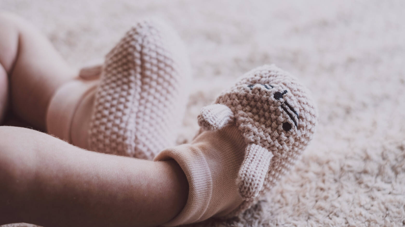 Lähikuva vauvan jaloista, joissa sukat ja neulotut puputossut.