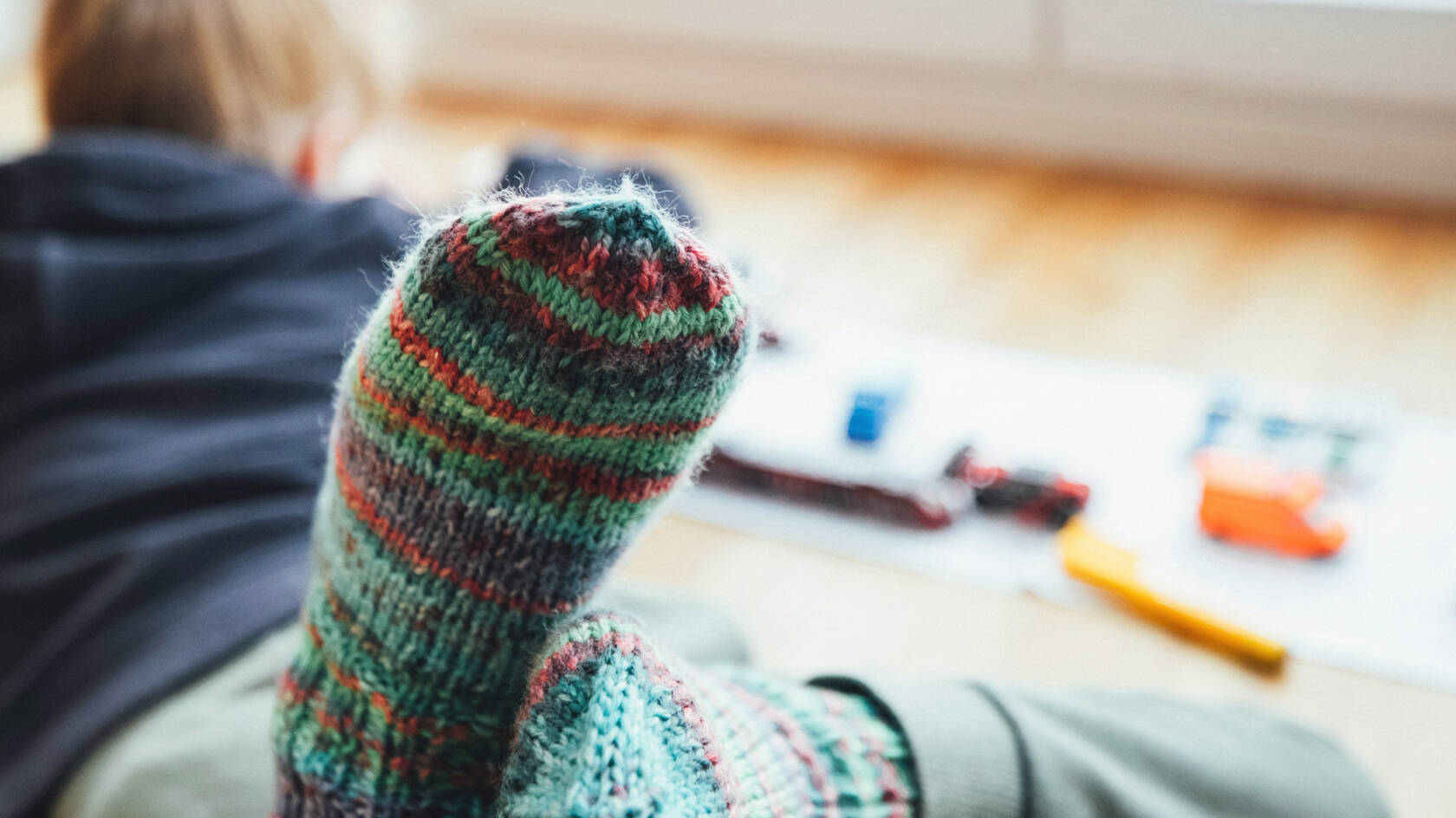 lapsi leikkii lattialla, kuvassa näkyy hänen villasukka