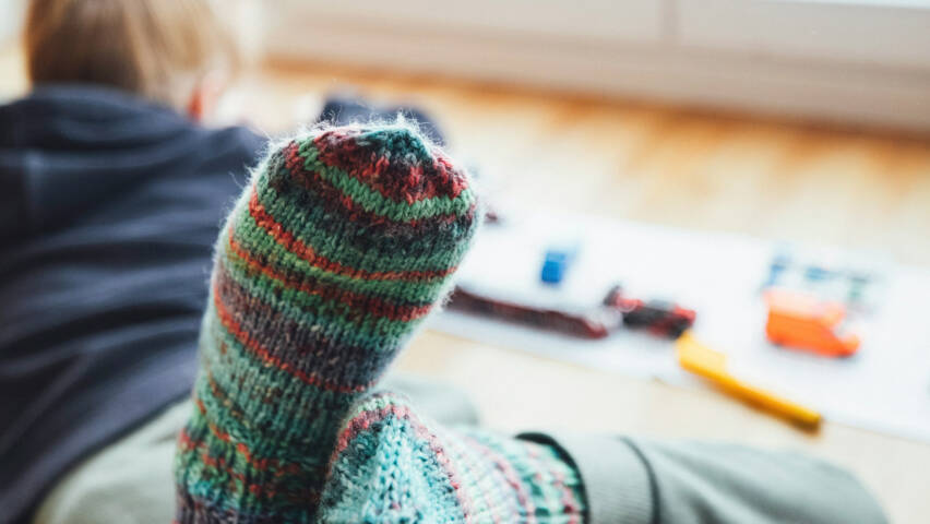 lapsi leikkii lattialla, kuvassa näkyy hänen villasukka