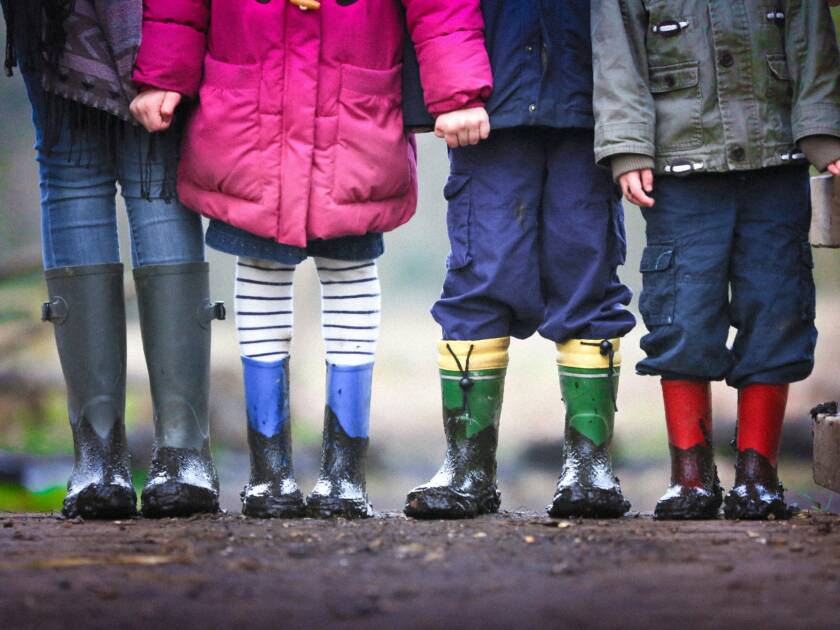 Puolikuva rivissä seisovista lapsista. Lapsilla on värikkäät kumisaappaat ja vaatteet.