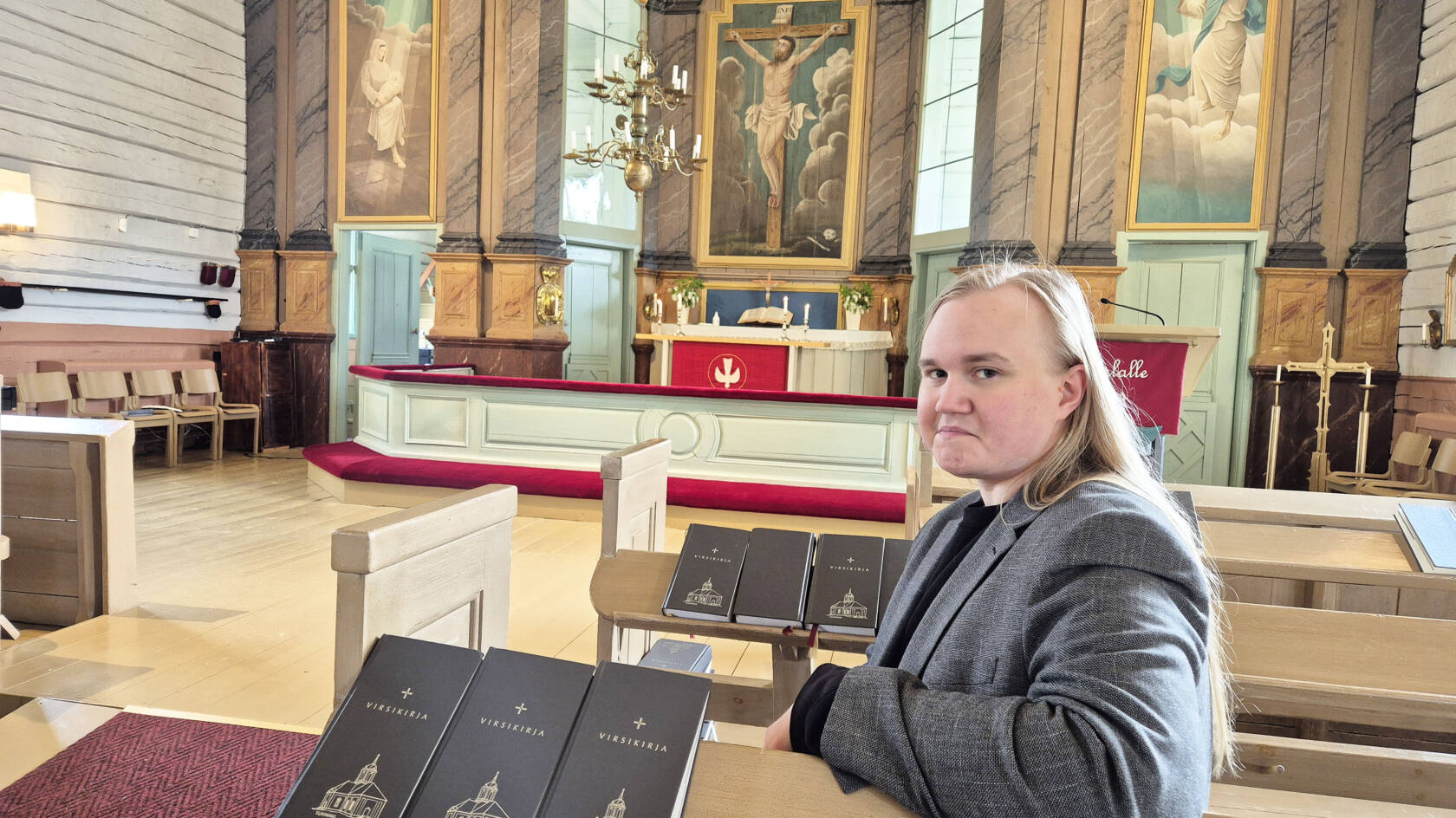 Miika Väänänen istuu Ylikiimingin kirkon penkissä taustallaan kirkon alttari.