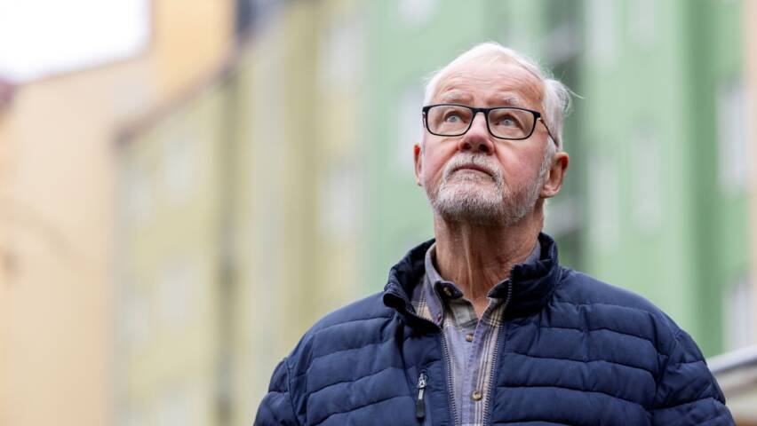 Silmälasipäinen ikääntynyt mies katsoo yläviistoon.